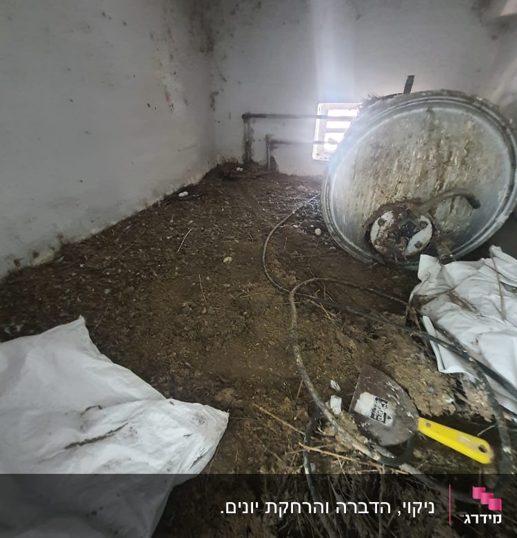 חדר עם קיר לבן, כלי עבודה וחפצים על הרצפה